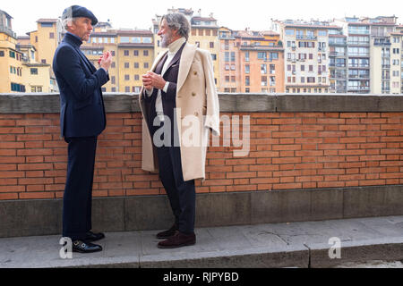 Zwei elegant elegant gekleidete Herren im Gespräch am Ufer des Flusses Arno Florenz Italien eingerückt Stockfoto