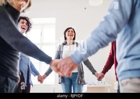 Mittelteil von Menschen in einem Kreis stehen und halten sich an den Händen während der Therapie. Stockfoto