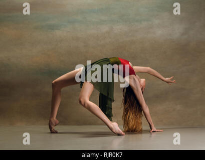 Die junge Frau tanzen im zeitgenössischen Stil auf grauem Hintergrund. Moderne Tänzerin im Studio. Eleganz, Anmut und Performance Concept Stockfoto