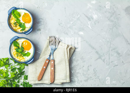 Gebackene Eier in blau Keramik Backformen. Portioniert Auflauf aus Gemüse und Eier in der italienischen oder französischen Stil. Eier kokot cocotte Frühstück. Top Stockfoto
