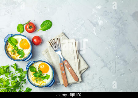 Gebackene Eier in blau Keramik Backformen. Portioniert Auflauf aus Gemüse und Eier in der italienischen oder französischen Stil. Eier kokot cocotte Frühstück. Top Stockfoto