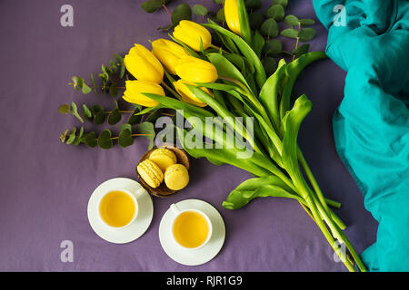 Gelbe Tulpen und zwei Tassen Tee im Bett Stockfoto