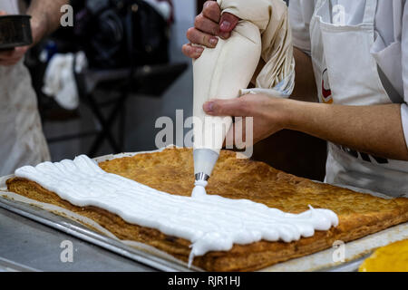 Gebäck mit der Hülse sahne Kuchen hinzufügen Stockfoto