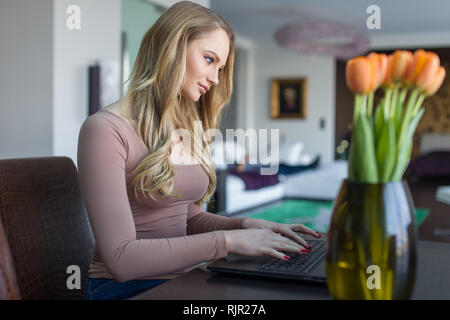 Blonde Frau Tippen auf Laptop zuhause, online-Kommunikation Stockfoto