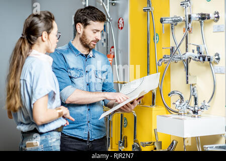 Junges Paar Auswahl dusche Wasserhahn in der Nähe von der schönen Schaufenster der Sanitär Shop Stockfoto