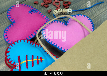 Papiertüte voller Souvenirs und handgefertigten Herz Liebesbriefe auf rustikalen Holzmöbeln Hintergrund. Liebe, Beziehung, Valentinstag, gebrochene Herzen Konzept Stockfoto