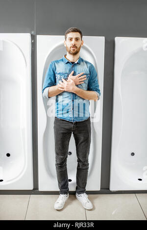 Lustige Porträt eines Mannes in der Badewanne liegend, während neue sanitäre Auswahl im Sanitär Shop Stockfoto