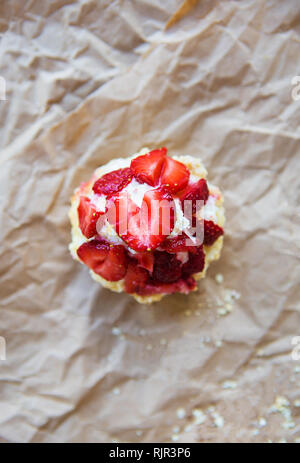 Schöne Muffin mit frischen Erdbeeren liegt auf Handwerk Papier, close-up. Stockfoto