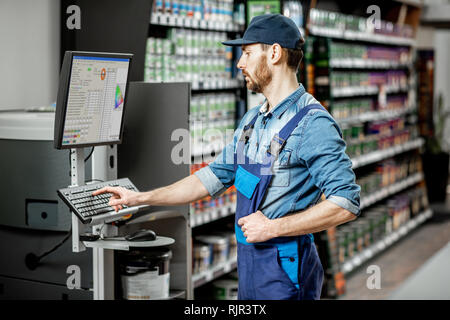 Schöner Mann arbeiten mit professioneller Ausrüstung für die Färbung in der Abteilung mit den Farben des Gebäudes Supermarkt Stockfoto