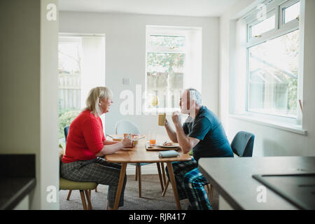 Reifes Paar sind mit Frühstück zusammen am Esstisch in Ihrem Haus. Stockfoto