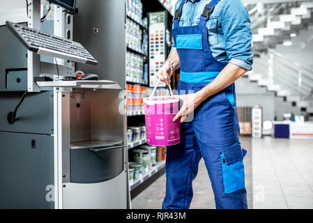 Arbeiter in Uniform, Eimer mit Farbe in der Maschine für die Färbung in das Gebäude shop Stockfoto