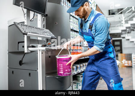 Arbeiter in Uniform, Eimer mit Farbe in der Maschine für die Färbung in das Gebäude shop Stockfoto