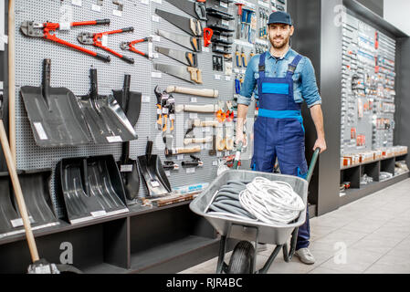 Porträt einer stattlichen Arbeiter in Uniform stehend mit schubkarre in der Nähe der Vitrine mit Garten im Shop Stockfoto