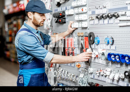 Stattliche Elektriker in der berufsbekleidung Auswahl elektrische Waren im Gebäude shop Stockfoto