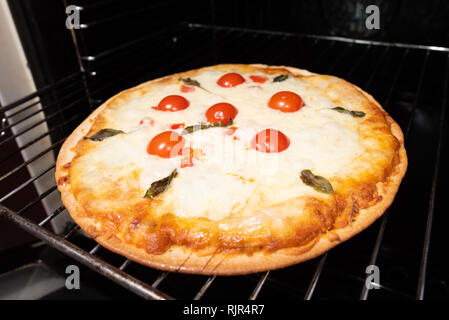 Pizza backen closeup mit Tomaten und Käse aus dem Ofen Stockfoto