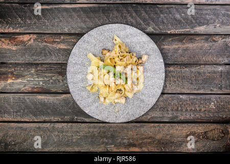 Italienische Pasta Fettuccine mit Käse, Huhn und Champignons, serviert auf der schönen Keramikplatte. Stockfoto