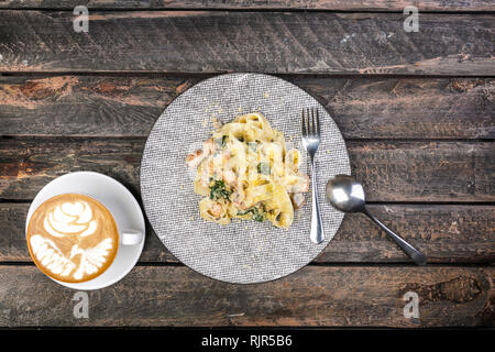 Fettuccine Pasta mit Meeresfrüchten in alten Holztisch, Ansicht von oben. Mit Besteck und eine Tasse Kaffee serviert. Stockfoto