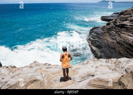 Frau an der felsigen Küste erkunden, Spucken Höhlen, Oahu, Hawaii Stockfoto