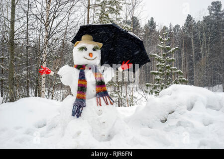 Lustiger Schneemann mit Schirm. Stockfoto