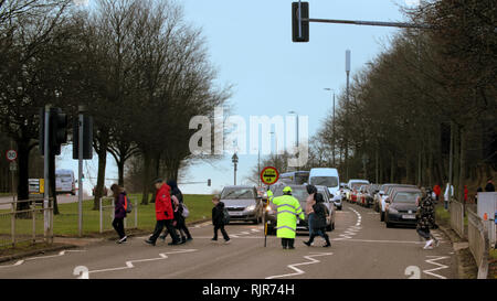 A82 Great Western Road, Glasgow, Schottland, Großbritannien einen Lutscher Dame hilft Schülern und Eltern über eine befahrene Straße A82 Stockfoto