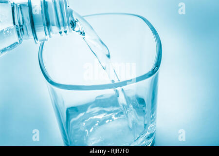 Klares Wasser fließt aus der Flasche in das Glas. Toning. Blur Stockfoto