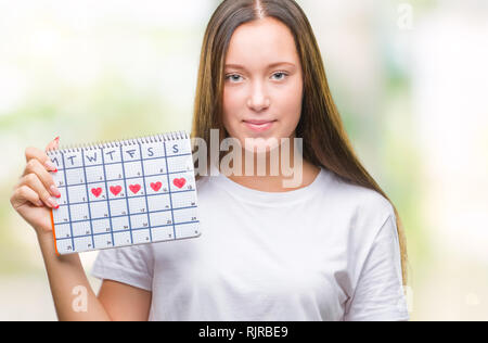 Junge kaukasier Frau mit Menstruations Kalender über isolierte Hintergrund mit einem selbstbewussten Ausdruck auf Smart Face denken Ernst Stockfoto