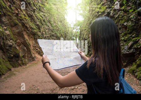 Rückseite der jungen Reisenden sehen Sie die Karte in den tiefen Wald, Hellfire Pass in Kanchanaburi, Thailand, Reise und Verkehr Konzept Stockfoto