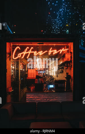 London, Großbritannien - 26 Januar, 2019: Beleuchtete Fenster und Leuchtreklame auf eine Coffee Bar in Canary Wharf an einem regnerischen Abend. Canary Wharf ist ein beschäftigter Finanzielle ein Stockfoto