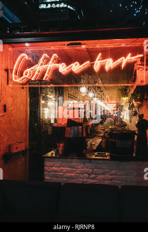 London, Großbritannien - 26 Januar, 2019: Beleuchtete Fenster und Leuchtreklame auf eine Coffee Bar in Canary Wharf an einem regnerischen Abend. Canary Wharf ist ein beschäftigter Finanzielle ein Stockfoto