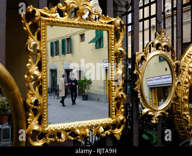 Zwei elegant elegant gekleidete Herren im Gespräch in Golden verzierten Spiegel außerhalb eines shop Florenz Italien hängenden wider Stockfoto