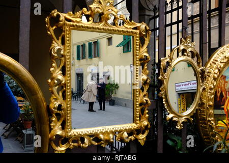 Zwei elegant elegant gekleidete Herren im Gespräch in Golden verzierten Spiegel außerhalb eines shop Florenz Italien hängenden wider Stockfoto