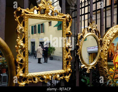 Zwei elegant elegant gekleidete Herren im Gespräch in Golden verzierten Spiegel außerhalb eines shop Florenz Italien hängenden wider Stockfoto