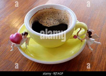 Tasse lächelnd Form schwarzer Kaffee mit zwei süße Mini, Amor Mädchen Figürchen auf hölzernen Tisch Stockfoto