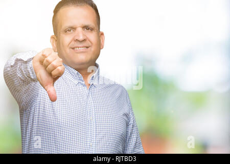 Mittleres Alter arabischer Geschäftsmann über isolierte Hintergrund unzufrieden und wütend, Ablehnung und negativ mit Daumen nach unten Geste. Schlechte expressio Stockfoto