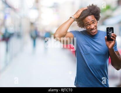 Afro-amerikanische Mann, gebrochen Smartphone über isolierte Hintergrund mit Hand betonte am Kopf, mit Scham und Überraschung Gesicht schockiert, wütend und Frust Stockfoto