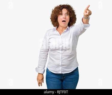 Schöne Mitte ager senior Geschäftshotels Frau über isolierte Hintergrund zeigt mit Finger vor überrascht, offenem Mund erstaunt Ausdruck, etwas in Stockfoto