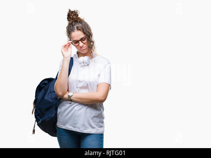 Junge brünette Studentin Mädchen mit Rucksack und Kopfhörer über isolierte Hintergrund denken müde und mit Depressionen Probleme mit Cr gelangweilt Stockfoto