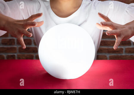 Nahaufnahme der Wahrsager Hand über die glühende Glaskugel Rot Schreibtisch Stockfoto