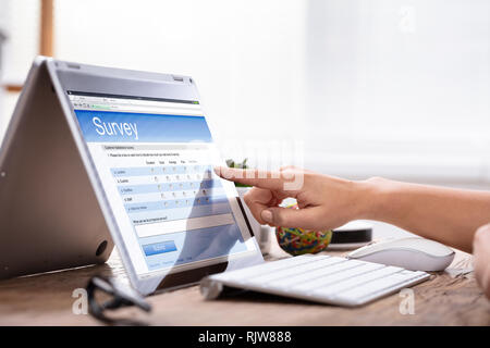 Nahaufnahme der Hand zeigen eine Geschäftsfrau, die an der Umfrage Formular auf Laptop Stockfoto