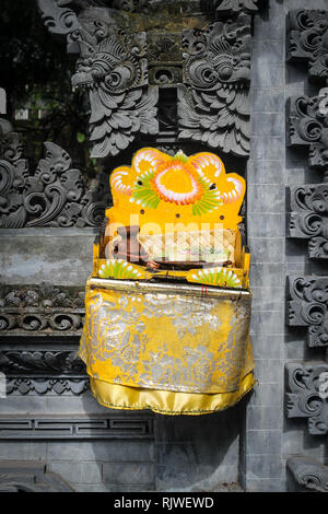 BALI, Indonesien - November 21, 2013: Balinesische Hindu Angebote namens Canang durch eine Kuh am Strand gegessen. Canang Sari ist einer der täglichen Angebote mad Stockfoto