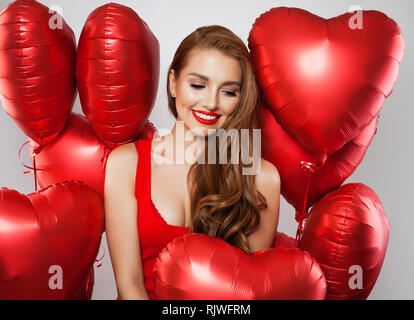 Lächelnde Frau mit Ballons auf weißem Hintergrund. Geburtstag Valentinstag Party Feier Konzept Stockfoto