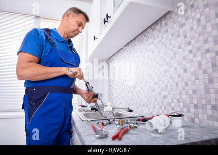 Seitenansicht eines Klempners zur Festsetzung Wasser in Küche Tippen Stockfoto