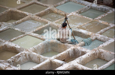 Mаn arbeiten als Tanner in alten Tanks bei Leder Gerbereien mit Farbe. in der alten Medina - Chouara Gerberei, Fes el Bali. Fez, Marokko Stockfoto