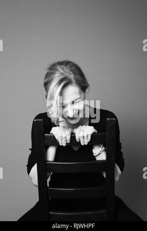 Porträt der schönen Frau in einem schwarzen Kleid vor grauem Hintergrund Stockfoto