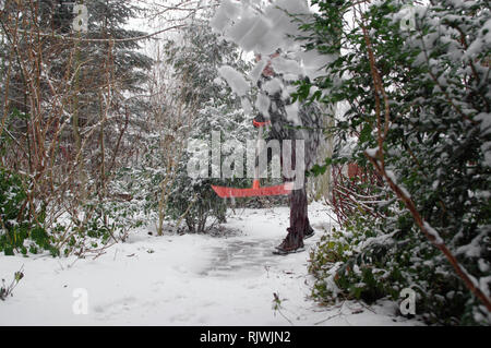 Schnee entfernen auf Bürgersteig in Home Garten. Winter saison arbeiten. Stockfoto