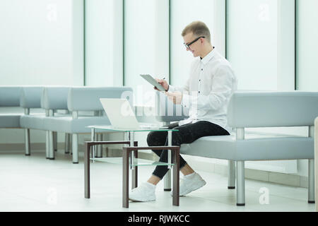 Mitarbeiter des Unternehmens liest einen Business Document im Büro Lobby sitzen Stockfoto