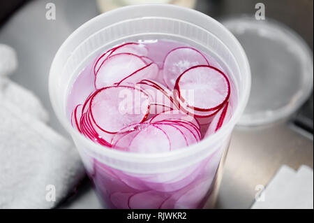 Radieschen in einem weißen Behälter mit Wasser füllten sie frisch zu halten. Stockfoto