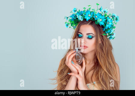 Schöne junge Schönheit Frau mit geschlossenen Augen, Kopfbügel der Anemone Blumen auf dem Kopf mit Flasche Parfüm Holding riechen Blumig Süß Aroma Ihrer n Stockfoto