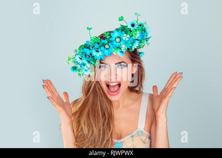 Enge bis sehr verärgerte Frau schreiend in Horror mit Stirnband aus Blumen. Frustrierte junge Dame in Nervenzusammenbruch betont isolierte Hellblau Stockfoto