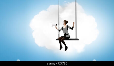 Frau mime im schwarzen Anzug sitzt auf Swing. Mixed Media Stockfoto